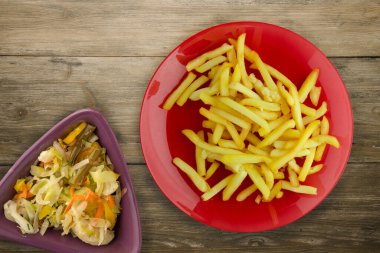  Ahşap arka planda patates kızartması. Sebze salatası manzaralı kırmızı tabakta patates kızartması.