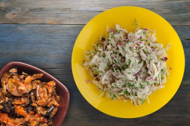 salata daikon, soğan ve dereotu mavi gri ahşap arka planda. Vejetaryen salsd soslu sarı tabakta salata.