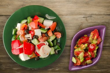 Kahverengi ahşap arka planda Yunan salatası. Vejetaryen salata manzaralı yeşil tabakta Yunan salatası. sağlıklı yiyecekler