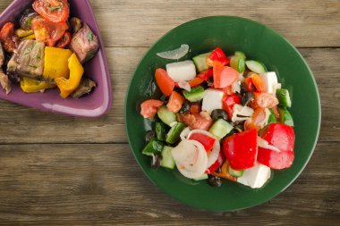 Kahverengi ahşap arka planda Yunan salatası. Vejetaryen salata manzaralı yeşil tabakta Yunan salatası. sağlıklı yiyecekler
