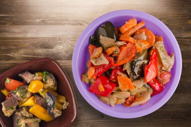 Kahverengi ahşap arka planda sebze güveci. Mor tabakta Bulgar güveci ve vejetaryen salata üstü manzarası