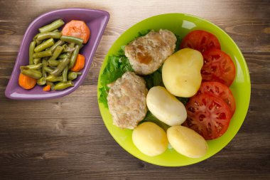 Limonlu patatesli pirzola ve sebze salatası. Kahverengi ahşap arka planda patatesli pirzola