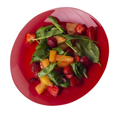 Çilekli salata, ananas ve kırmızı tabakta ıspanak. Beyaz arka planda izole edilmiş meyve vejetaryen salatası. Vejetaryen salatası.
