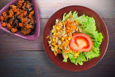 Havuçlu tavuk mideli salata, mısır ve sebze salatası manzaralı kahverengi tabakta salata. Mor ahşap arka planda sebzeli tavuk salatası