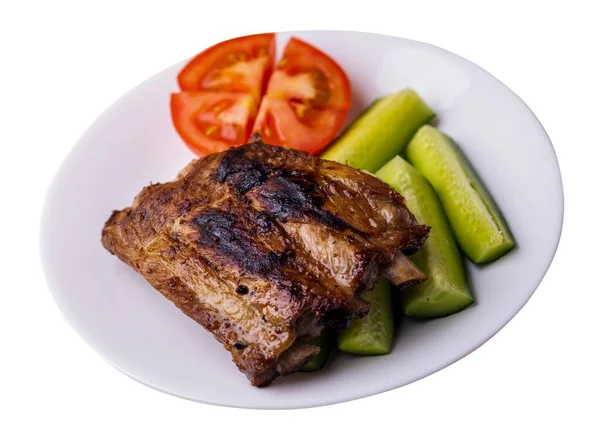grilled pork ribs with sliced cucumbers and tomatoes on white plate. pork ribs isolated on white background. ribs grill top side view