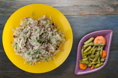 salata daikon, soğan ve dereotu mavi gri ahşap arka planda. Vejetaryen salsd soslu sarı tabakta salata.