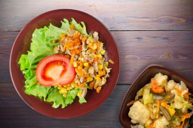 Havuçlu tavuk mideli salata, mısır ve sebze salatası manzaralı kahverengi tabakta salata. Mor ahşap arka planda sebzeli tavuk salatası