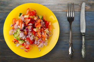 Vejetaryen yemeği. Biberli salata, domates, soğan, sarı tabakta brokoli. Mavi gri ahşap arka planda vegan salatası