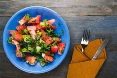 Bıçak ve çatalla vejetaryen yemeği. Domates, soğan, mavi tabakta rezene mavi gri ahşap arka planda. sağlıklı yiyecek üst görünümü