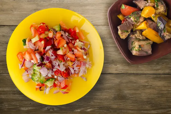 Vejetaryen yemeği. Biberli salata, domates, soğan, sarı tabakta brokoli vejetaryen salatası. Tahta arka planda vejetaryen salatası