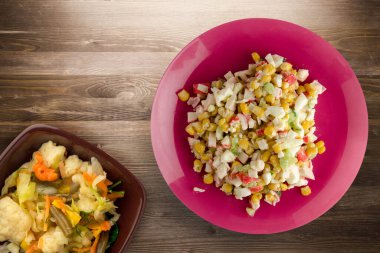 Kırmızı tabakta sebze salatası manzaralı yengeç salatası. Kahverengi ahşap arka planda yengeç salatası