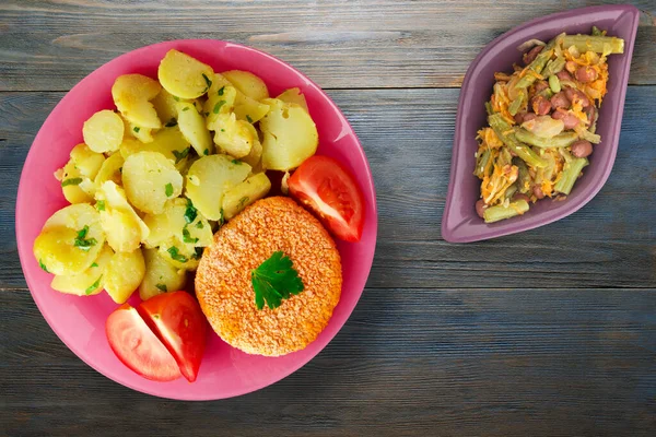 肉丸子 灰色蓝色木制背景的土豆 肉丸子 粉红色盘子里有一片西红柿 上面有蔬菜沙拉 — 图库照片