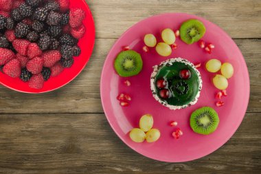 Kek ve meyve üzümleri, kivi, ahşap zemin üzerinde nar. Meyveli tatlı pembe tabak manzaralı.