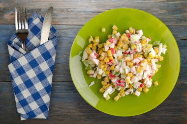 Kireç tabağında çatal ve bıçaklı yengeç salatası. Mavi gri ahşap arka planda yengeç salatası.