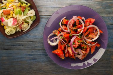 Vejetaryen yemeği. Domates, soğan, mor tabakta rezene mavi gri ahşap arka planda. sağlıklı yiyecek üst görünümü