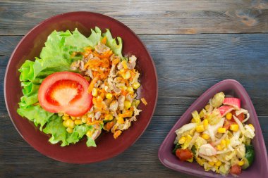 Tavuk mideli salata, havuç, mısır ve salata. Kahverengi tabak manzaralı. Mavi ahşap arka planda sebzeli tavuk salatası.