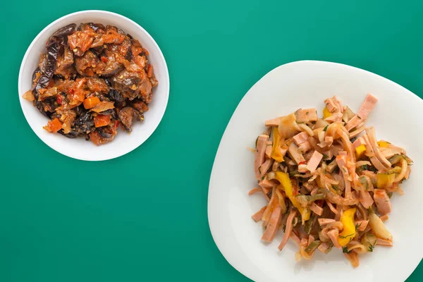 Yeşil arka planda sebze salatası olan beyaz tabakta Berlin salatası. Sosis, salatalık, biber soslu salata. .