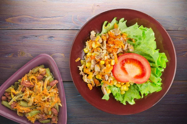 Havuçlu tavuk mideli salata, mısır ve sebze salatası manzaralı kahverengi tabakta salata. Mor ahşap arka planda sebzeli tavuk salatası