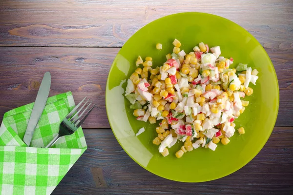 Kireç tabağında yengeç salatası, çatal ve bıçak manzaralı. Mor ahşap arka planda yengeç salatası