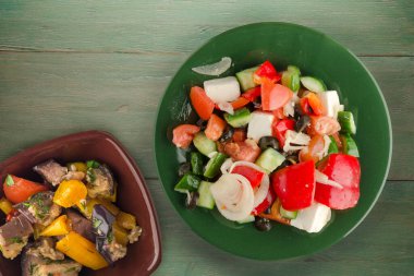 Yeşil ahşap arka planda Yunan salatası. Vejetaryen salata manzaralı yeşil tabakta Yunan salatası. sağlıklı yiyecekler