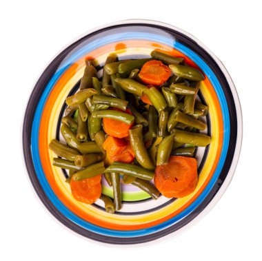 Beyaz mavi kırmızı tabakta sarımsaklı ve havuçlu yeşil fasulye. Beyaz arka planda izole edilmiş. Havuç üst görüşlü yeşil fasulye. sağlıklı vejetaryen yemekleri