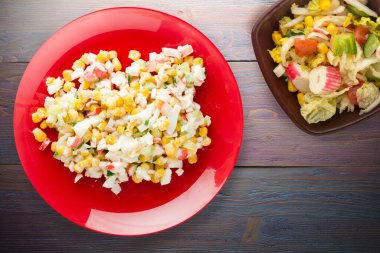 Kırmızı tabakta, vejetaryen salatası manzaralı yengeç salatası. Mor ahşap arka planda yengeç salatası