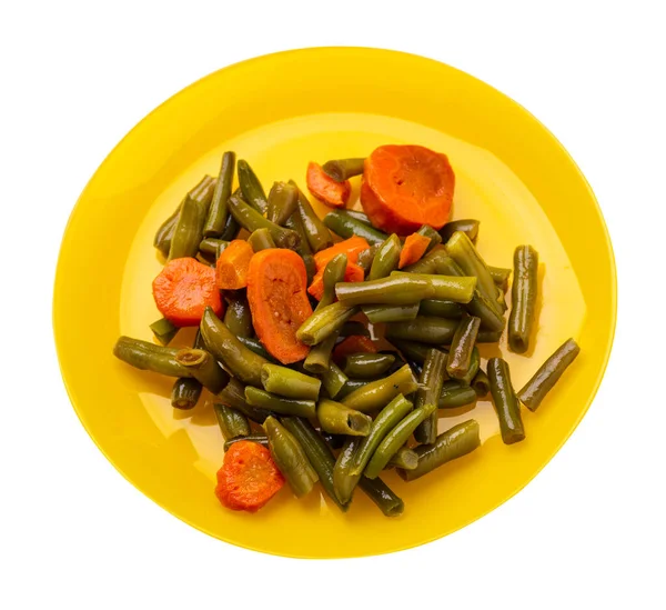 Sarı tabakta sarımsaklı ve havuçlu yeşil fasulye. Beyaz arka planda izole edilmiş. Havuç manzaralı yeşil fasulye. sağlıklı vejetaryen yemekleri