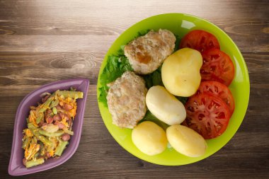 Limonlu patatesli pirzola ve sebze salatası. Kahverengi ahşap arka planda patatesli pirzola