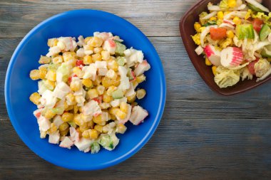 Sebze salatası manzaralı lacivert tabakta yengeç salatası. Gri ve mavi ahşap arka planda yengeç salatası