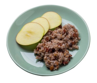 Üzümlü çavdar gevreği ve açık yeşil tabakta elmalar. Öfke taneleri beyaz arka planda izole edilmiş. Sağlıklı kahvaltı manzarası