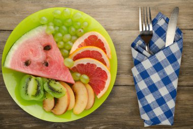 Doğuştan ahşap arka planda kesilmiş meyve. Açık yeşil bir çatal üzerinde dilimlenmiş meyve ve bıçak üst görünümü