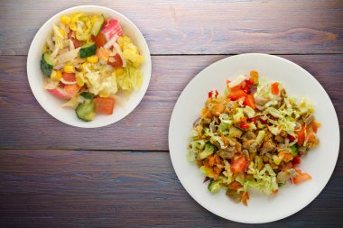 Tavuk mideli salata ile sebze havuç, soğan, biber, lahana, domates, brokoli. Mor ahşap arka planda beyaz tabakta tavuklu salata.