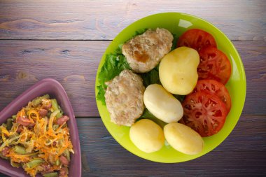 Limonlu patatesli pirzola ve sebze salatası. Patatesli pirzola ve mor ahşap arka plan.