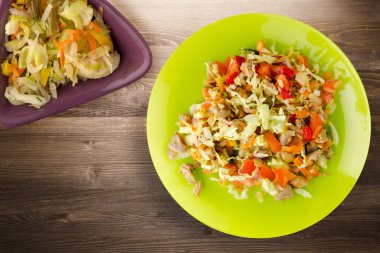 Tavuk mideli salata ile sebze havuç, soğan, biber, lahana, domates, brokoli. Kireç tabağında tavuk ve kahverengi ahşap arka planda salata. sağlıklı salatalar üst görünüm