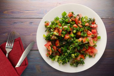 Çatal ve bıçak manzaralı vejetaryen yemekleri. Domates, soğan, beyaz tabakta rezene mor ahşap arka planda. sağlıklı yiyecekler