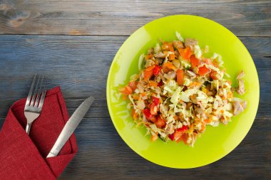 Tavuk mideli salata ile sebze havuç, soğan, biber, lahana, domates, brokoli. Mavi ahşap arka planda sarı tabakta tavuklu salata. Çatal ve bıçak manzaralı vejetaryen salatası.