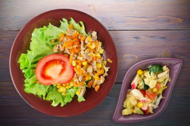 Havuçlu tavuk mideli salata, mısır ve sebze salatası manzaralı kahverengi tabakta salata. Mor ahşap arka planda sebzeli tavuk salatası
