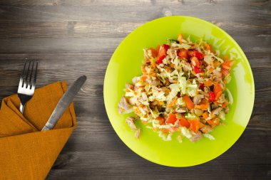 Tavuk mideli salata ile sebze havuç, soğan, biber, lahana, domates, brokoli. Limonlu tavuklu salata siyah ahşap arka planda çatal ve bıçak manzaralı.