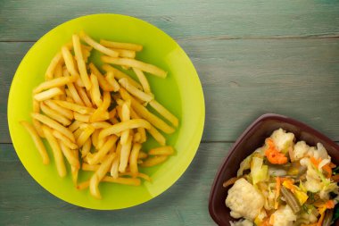 Patatesleri yeşil ahşap arka planda kızart. Limonlu patates kızartması ve sebze salatası.