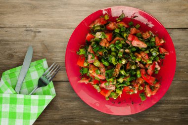 Çatal ve bıçaklı vejetaryen yemeği. Domates, soğan, kırmızı tabakta rezene kahverengi ahşap arka planda. sağlıklı yiyecekler