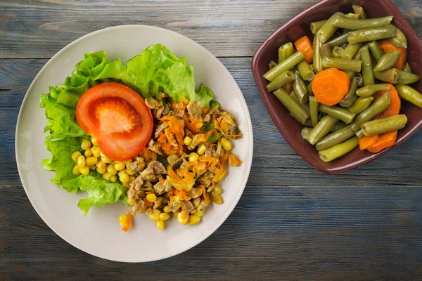 Salad with chicken stomachs with carrots and corn and salad on light gray plate top view. chicken salad with vegetables on blue wooden background — Stock Image Salad Chicken Stomachs Carrots Corn Salad Light Gray Plate Top Stock Photo