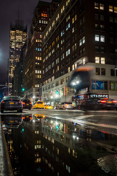 NEW YORK, USA - FEBRUARY 22, 2018: Cyclist riding at night in the streets of Time Square in New York in the rain