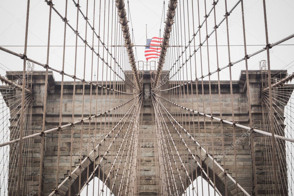 Details of the architecture of the famous Brooklyn Bridge with the American flag