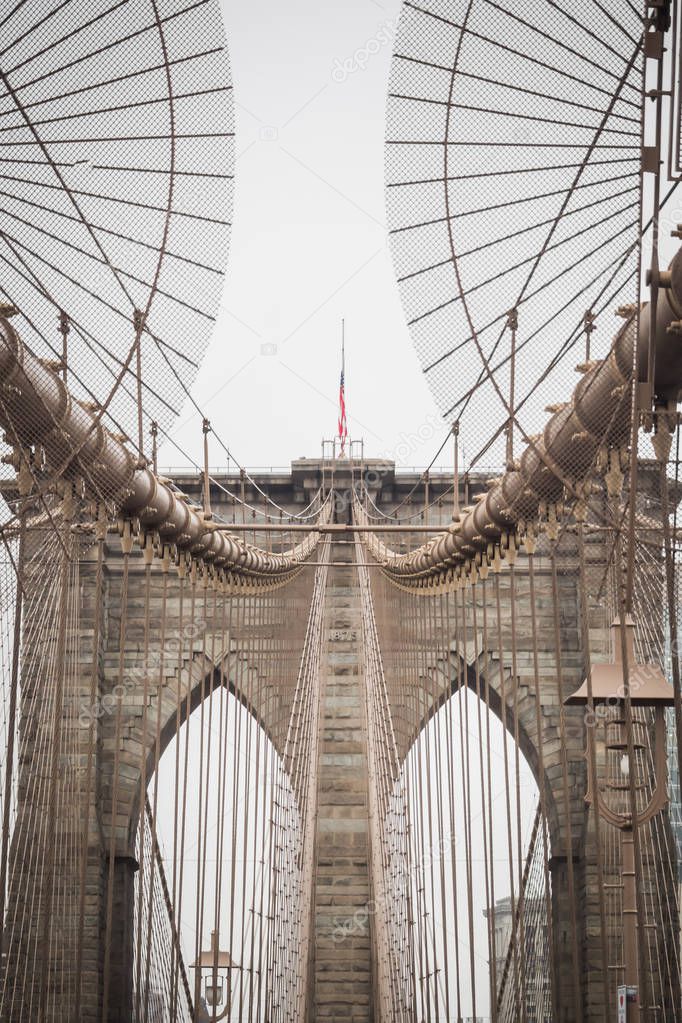 Details of the Brooklyn Bridge architecture with the American flag at the top of the arch