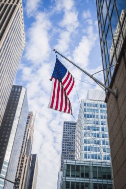 Güzel mavi gökyüzünde New York'ta Manhattan sokaklarında gökdelenler arasında yüzen Amerikan bayrağı