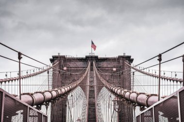 New York'taki ünlü Brooklyn Köprüsü'nün mimarisinin sürükleyici dramatik manzarası, fırtınalı bir gökyüzünün altında