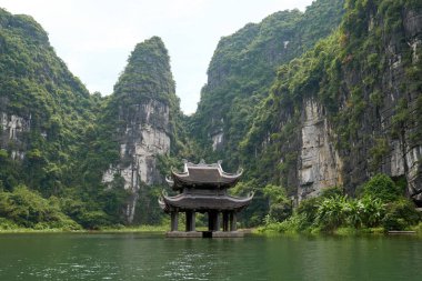 Nehirdeki küçük tapınak karst dağlarıyla çevrili. Trang 'da güzel manzara Tam Coc, Vietnam' da bir tekne turu.
