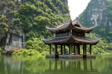 Nehirdeki küçük tapınak karst dağlarıyla çevrili. Trang 'da güzel manzara Tam Coc, Vietnam' da bir tekne turu.