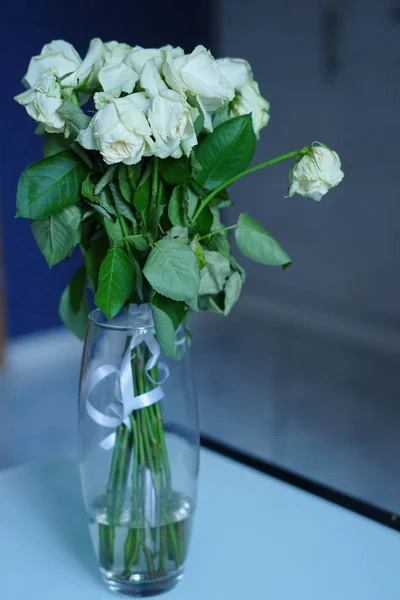 White roses in a transparent glass vase.