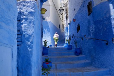 Yerel bir kadın Fas 'ta Chefchaouen mavi bir şehirde eski bir Medina sokaklarında yürüyor.